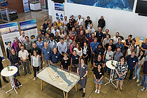 Eine Gruppe Menschen steht in einem Foyer. Alle schauen in die Kamera.