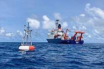 Eine Messboje und ein Forschungsschiff auf dem Meer