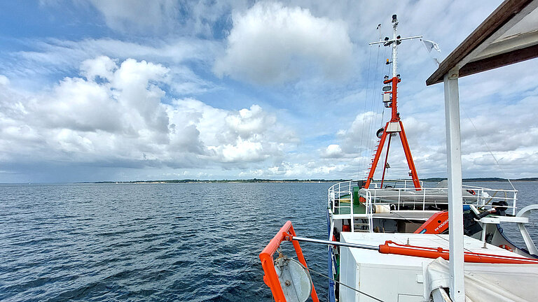 Ein Schiff auf dem Meer, im Hintergrund die Küste