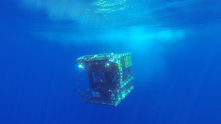 Ein gelber Tauchroboter taucht in blaues Wasser