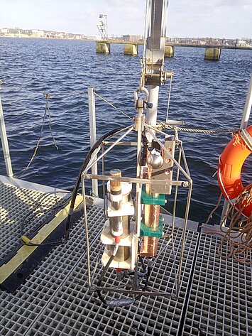 Ein HydroC und ein MicroCAT hängen in einem Metallgestell, im Hintergrund Wasser.