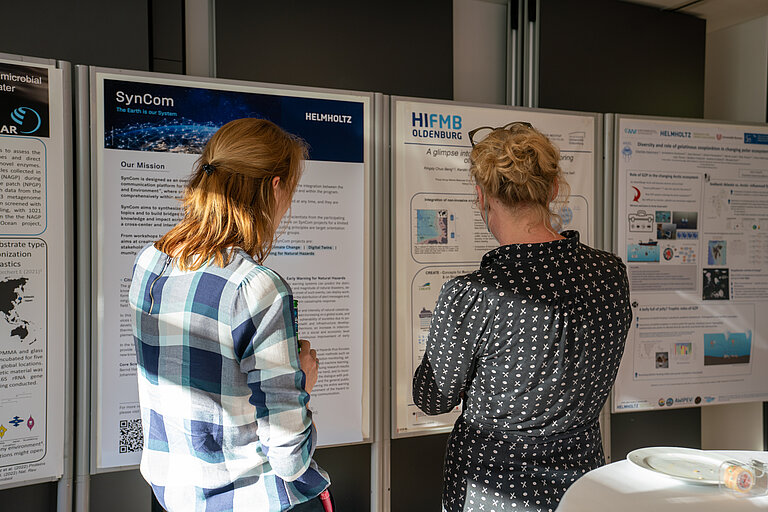 Zwei Wissenschaftlerinnen stehen vor einem wissenschaftlichen Poster.