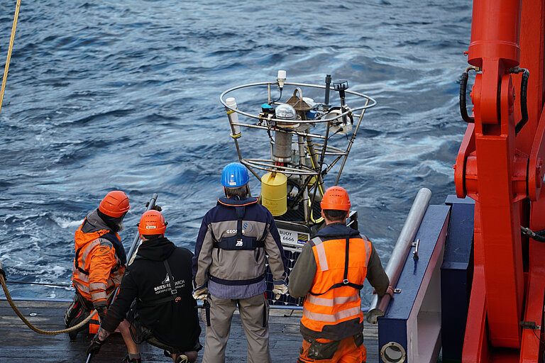 Four crew members of Maria S. Merian secure the PAP buoy to the stern crane.