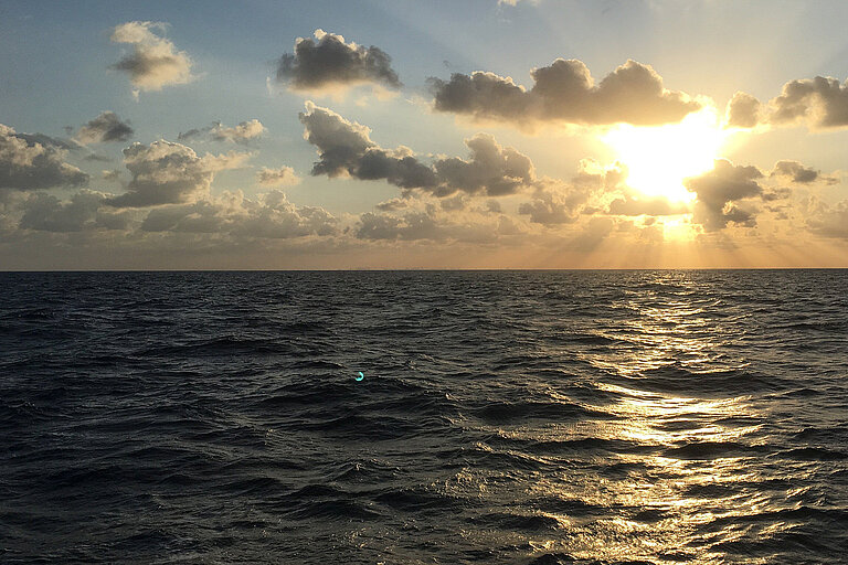 Meeresoberfläche und Sonne, die durch Wolken scheint